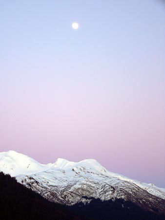 beautiful image of the moon rising over the mountains in southeast alaska